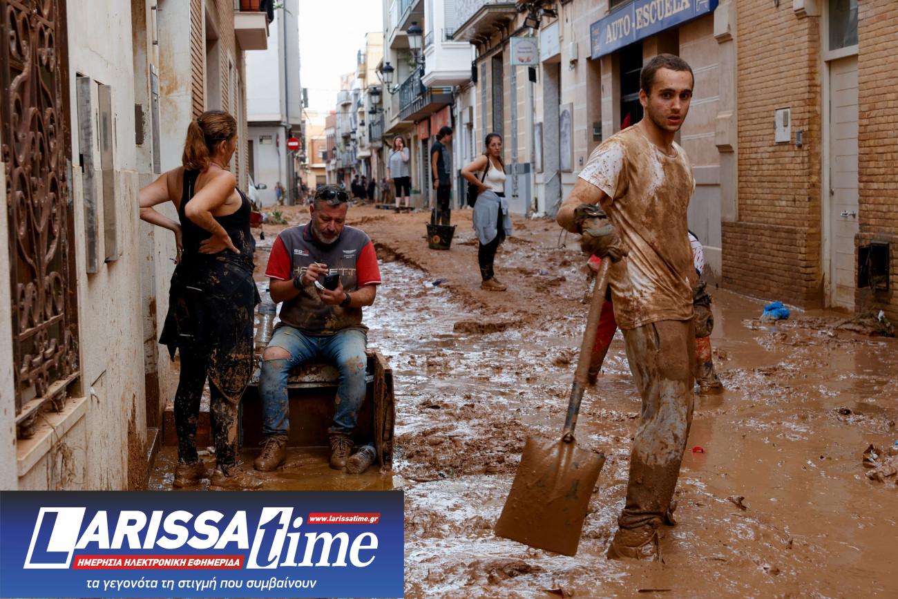 Εικόνα δείχνει κατοίκους της Παϊπόρτα στην Ισπανία να στέκονται σε έναν από τους λασπωμένους δρόμους μετά τη φονική πλημμύρα 