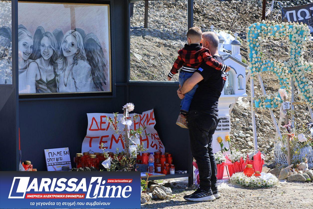 Εικόνα που δείχνει πατέρα με παιδί μπροστά σε πορτρέτο των αδικοχαμένων διδύμων και της ξαδέλφης τους που επέβαιναν στο μοιραίο τρένο